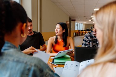 Genç Asyalı kız üzerine odaklanmış çok ırklı bir grup öğrenci bir masada birlikte çalışıyor ve ortak bir proje üzerinde çalışıyorlar. Üniversitede çeşitlilik ve kapsama