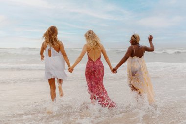 Üç genç kadının el ele tutuşup sahilde denize doğru koştuğu çok ırklı bir grup. Yazın arkadaşlarıyla seyahat ediyor..