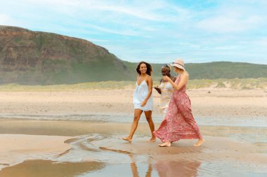 Bir yaz günü kumsalda birlikte yürüyen bir grup arkadaş. Yaz tatili boyunca çok ırklı genç kızlar grubu.