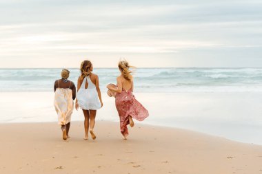 Sahilde yürüyüşün tadını çıkaran üç arkadaş grubu..
