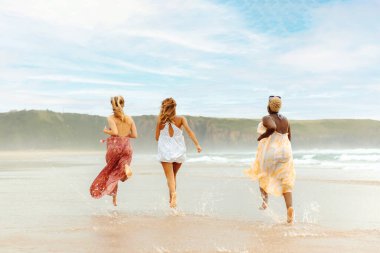 Bir yaz günü sahilde birlikte koşan üç genç kız. Yaz tatilinin tadını çıkaran çok ırklı bir grup kadın..