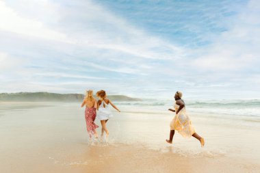 Bir yaz günü sahilde birlikte koşan üç genç kız. Yaz tatilinin tadını çıkaran çok ırklı bir grup kadın..