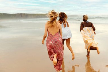 Bir yaz günü sahilde birlikte koşan üç genç kız. Yaz tatilinin tadını çıkaran çok ırklı bir grup kadın..