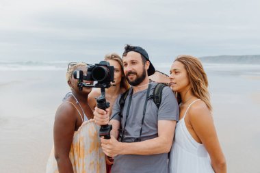 Film yapımcısı, kameraman ve fotoğrafçı bir jimnastik aletine tutunarak, kamera görüntülerini mankenlere veya aktrislere gösterir.