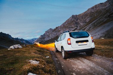 4WD 'li beyaz SUV' nin dağlardaki toprak bir pistte sürüşü. Macera gezisi ve etkinlik.