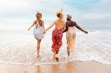 Üç kadın arkadaşın el ele tutuşup deniz kıyısında iyi vakit geçirdiği çok ırklı bir grup. Kadınlar arasındaki dostluk ve birlik. yaz gezisi.