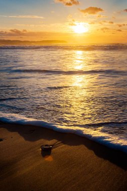 Sahilden gün batımında deniz manzarasının dikey fotoğrafı..