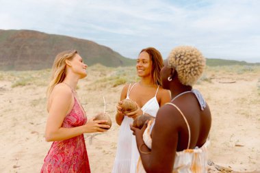 Hindistan cevizi suyu içen üç kadın arkadaştan oluşan çok ırklı bir grup ya da yaz plaj partisinde hindistan cevizi kabını konteynır olarak kullanan bir kokteyl.