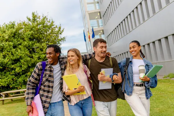 stock image a group of four friends and classmates with school supplies walk happily out of the school building.