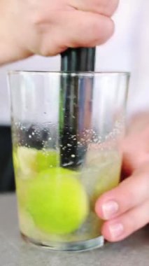 Tanınmayan barmen tipik bir Küba mojito 'su hazırlamak için limon, nane ve şekeri romla eziyor..