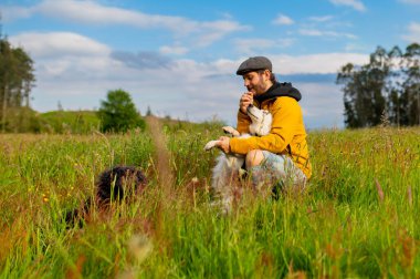 Kırsalda köpekleriyle yürüyüş yaparken eğlenen bir adam.