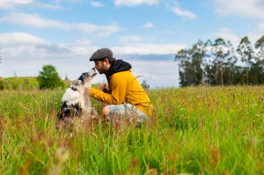 Sınırdaki köpeğiyle sahada oynayan ve antrenman yapan bir adam.