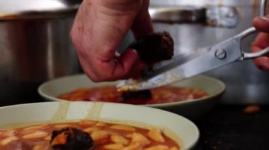 Tanınmaz haldeki aşçı, lezzetli bir tabak fasülye, puding ve pastırmalı fasulyeye eklemek için makas parçalarıyla siyah puding kesiyor.).