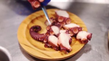 Bir ahtapot tapotunu pişirmek için ahtapotun dokunaçlarını dilimleyen uzlaşmaz bir aşçı..