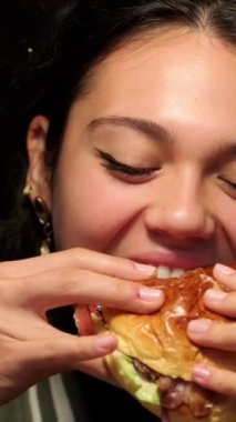 Lezzetli bir hamburgerin tadını çıkaran genç kadın