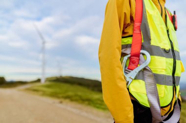 Emniyet kemeri takan mühendis ve rüzgar çiftliğinde çalışan yüksek görünürlüklü yelek.
