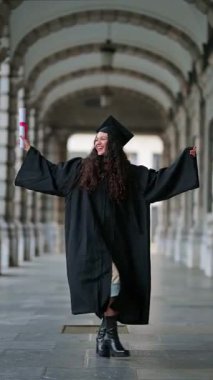 Üniversite kemerinin altında diplomayla mutlu mezuniyet dansları