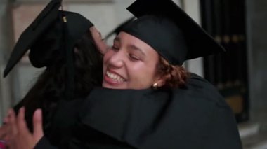 Mutlu üniversite mezunları sarılma ve diplomalarla kutluyor.