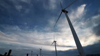 Rüzgar türbinleri dinamik ve bulutlu bir gökyüzü altında temiz enerji üretir.