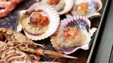 Sıcak bir restoranda leziz bir deniz ürünleri ziyafeti hazırlayan sulu deniz tarakları ve karides cızırtısı.