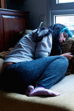 Depresyondaki genç kadın evdeki kanepede yatıyor.