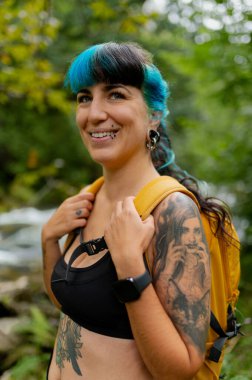 Mavi saçlı dövmeli yürüyüşçü Casano nehir yolu boyunca yürürken gülümsüyor. Cabrales, İspanya, doğanın huzurunun tadını çıkarıyor.