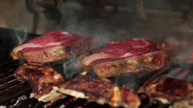 Lezzetli pirzola biftekleri ve ızgarada ızgara pirzola. Restoranın mutfağında duman yükseliyor.