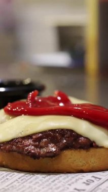 Profesyonel şef, erimiş peynirli, çıtır pastırmalı ve ketçaplı lezzetli bir ezme burger hazırlıyor.