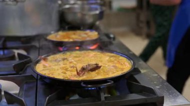 Yetenekli aşçılar otantik İspanyol paella 'sı yapıyorlar, profesyonel restoran mutfağında titizlikle geleneksel deniz ürünleri pilavı hazırlıyorlar.