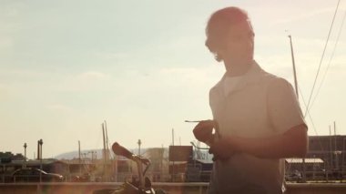 Şık güneş gözlüğü takan genç Hintli profesyonel bisiklet, marina arkaplanı şehir yaşam tarzını ve başarılı iş yaklaşımını gözler önüne seriyor.