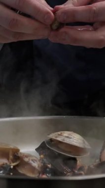 Şef taze midye ve midyeleri ustalıkla temizler ve hazırlar. Deniz ürünleri için lezzetli bir taban oluşturur.