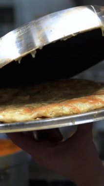 Kaliteli bir restoran mutfağında metal kapak kullanarak geleneksel İspanyol patates omletini ustalıkla çevirerek aşçılık uzmanlığını gösteriyor.