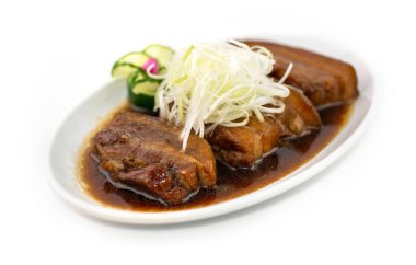 Üstünde bahar soğanı olan ağır ateşte pişmiş domuz göbeği.