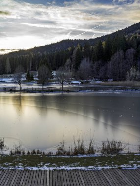 Kış dağı manzarası, donmuş göl, gün batımında.