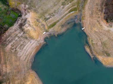 Dramatik bir kıyı şeridi ve park edilmiş bir teknenin yüksek açılı gölü. Havadan bakıldığında dramatik bir kıyı şeridi olan sakin bir göl görülüyor. Omerli İstanbul Türk Cekmekoy hava görüntülü insansız hava aracı 