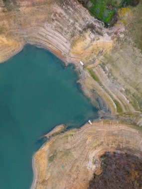 Katmanlı toprak oluşumlarıyla gölün kıyı şeridinin yüksek açılı görüntüsü. Bir göl kıyısının havadan çekilmiş görüntüsü çeşitli toprak tonlarını ve katmanlı jeolojik oluşumları gösteriyor.. 