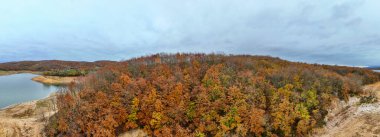 Sonbahar kıyı şeridi olan sakin bir göl manzarası. Yüksek açılı, sakin bir göl, sakin bir sonbahar manzarası..