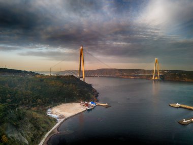 Yavuz Sultan Selim Köprüsü İstanbul Türkiye. Bir su yolu boyunca uzanan, nefes kesici bir köprü manzarası, muhtemelen bir liman ya da boğaz. Sunset Havacılık 'taki Su Yolu üzerindeki Çarpıcı Kablo Kalan Köprü 
