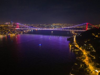 Geceleyin Boğaziçi Köprüsü Fatih Sultan Mehmet Köprüsü aydınlandı. Türkiye 'nin İstanbul kentindeki Boğaz Köprüsü' nün nefes kesici hava manzarası. Beykoz Türkiye güzel bir akşam fotoğrafı romantik, drone  