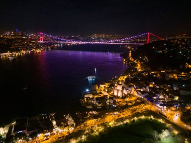 ANADOLU HISARI (ANADOLU HISARI) VE FATIH SULTAN MEHMET BRIDGE. İstanbul 'un su yollarına yayılan Boğaz Köprüsü' nün geceleyin hava görüntüsü. İstanbul 'un Gece Kenti Boğazı Köprüsü. 