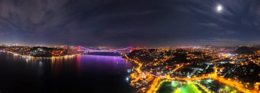 Panoramik İstanbul 'un Gece Boğazı Köprüsü: Göz kamaştırıcı bir hava manzarası. İstanbul Boğaz Köprüsü 'nün nefes kesen hava manzarası gece aydınlanarak kentin canlı ışıklarını yansıtıyor.  