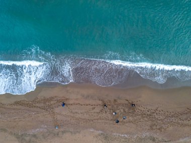 Turkuaz su ve kumdaki ayak izlerinin olduğu yüksek açılı bir sahil manzarası. Turkuaz okyanus suyuyla kumlu bir sahil buluşmasının havadan çekilmiş görüntüsü..