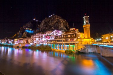 Amasya, Türkiye - Ağustos 2017: Türkiye 'nin Amasya kentindeki Yesilirmak Nehri' nin gece ve aynalı manzaralı eski Osmanlı evleri ve Saat Kulesi