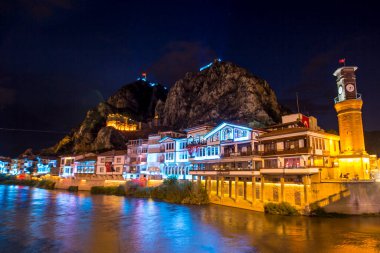 Amasya, Türkiye - Ağustos 2017: Türkiye 'nin Amasya kentindeki Yesilirmak Nehri' nin gece ve aynalı manzaralı eski Osmanlı evleri ve Saat Kulesi