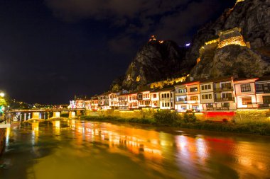 Amasya, Turkey - August, 2017: Old Ottoman houses and Clock Tower with night and mirrored view by the Yesilirmak River in Amasya, Turkey clipart