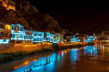 Amasya, Türkiye - Ağustos 2017: Türkiye 'nin Amasya kentindeki Yesilirmak Nehri' nin gece ve aynalı manzaralı eski Osmanlı evleri ve Saat Kulesi