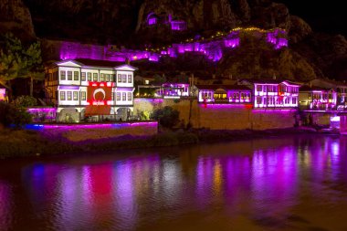 Amasya, Türkiye - Ağustos 2017: Türkiye 'nin Amasya kentindeki Yesilirmak Nehri' nin gece ve aynalı manzaralı eski Osmanlı evleri ve Saat Kulesi