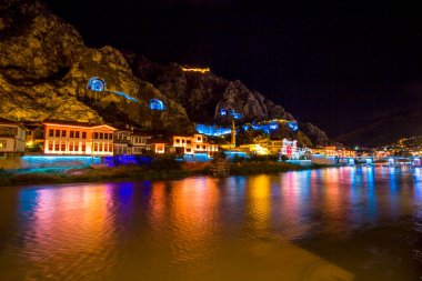 Amasya, Türkiye - Ağustos 2017: Türkiye 'nin Amasya kentindeki Yesilirmak Nehri' nin gece ve aynalı manzaralı eski Osmanlı evleri ve Saat Kulesi