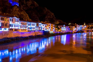 Amasya, Türkiye - Ağustos 2017: Türkiye 'nin Amasya kentindeki Yesilirmak Nehri' nin gece ve aynalı manzaralı eski Osmanlı evleri ve Saat Kulesi