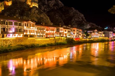 Amasya, Türkiye - Ağustos 2017: Türkiye 'nin Amasya kentindeki Yesilirmak Nehri' nin gece ve aynalı manzaralı eski Osmanlı evleri ve Saat Kulesi